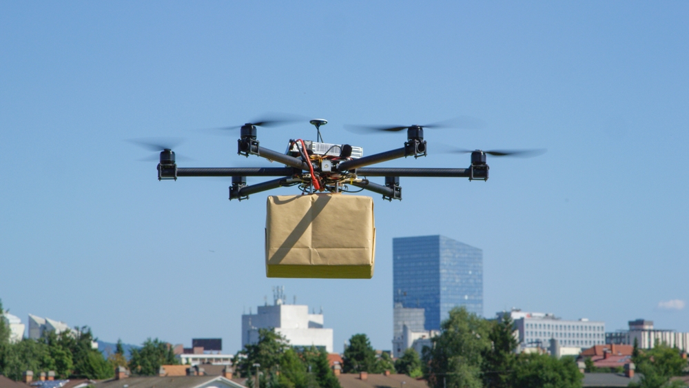 aerial delivery drone shown hovering holding a br - Robots Industriales, Qué son y Cómo elegirlos